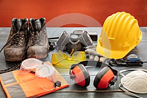 Work safety protection equipment. Industrial protective gear on wooden table, red color background