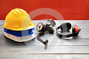 Work safety protection equipment. Industrial protective gear on wooden table, red color background