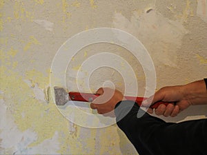 work with a scraper to clean the remnants of wallpaper from the wall