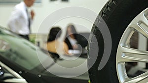 Work in the showroom. Sales Manager at the dealership works at a Desk. In the foreground of the car and wheel , the