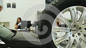 Work in the showroom. Sales Manager at the dealership works at a Desk. In the foreground of the car and wheel , the