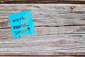 Work smart not hard concept. Sticky note reminder on wooden background.