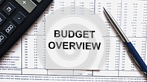 Work smarter text Budget Overview on white sheet with pen, calculator and tables photo