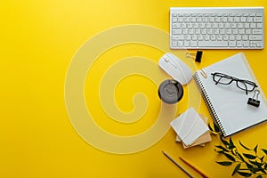 Work space desk layout with note pc keyboard coffee cup glasses bright color yellow background copy space. Modern office