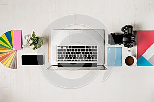 Work space for photographer, graphic designer. Flat lay of laptop, camera, colorchart, digital tablet, coffee cup, book, pencil o