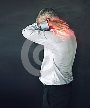 When work stress becomes physical. Studio shot of a mature man experiencing neck ache against a black background.