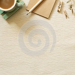 Work and study place. Cup of coffee, notepad, pencil, clip on beige fabric background