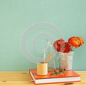 Work and study place. note book, pencil with floral decoration on wooden desk with green background