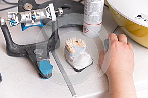 Work table of a dentistry technician with his hand on his mouse near gypsum denture.