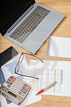 Work table at home with pen, papers, bills, charts, glasses, computer and calculator. Concept work at home, checking accounts,