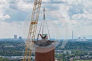 Aerial drone view of demolition of chimney, excavator working on smokestack. Small excavator destroying a tall chimney. Work on photo