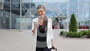 Work travel. Business woman with phone and suitcase near airport