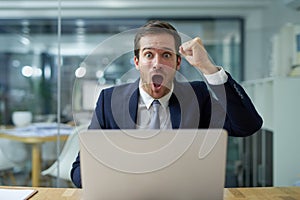 This work is unacceptable. Portrait of an angry businessman shouting and waving a fist while sitting at his laptop at a