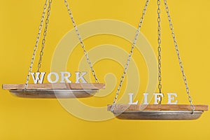 Work vs life. Balance concept. Scales on yellow background, close up