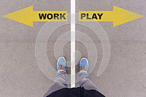 Work vs Play text arrows on asphalt ground, feet and shoes on fl