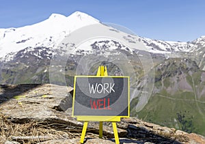 Work well symbol. Concept words Work well on beautiful black chalk blackboard. Beautiful mountain Elbrus blue sky background.