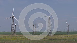 Work of wind turbines placed in the fields against a blue sky.