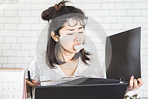 Workaholic Asian woman busy with working and eating sandwich at her office