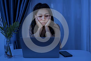 Workaholic business Asian woman working late at night feeling sleepy and tired sitting at desk with laptop