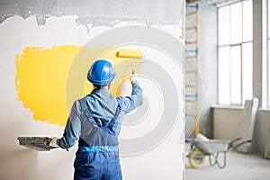 Workamn painting wall indoors