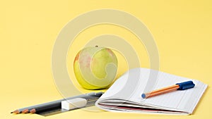 Workbook with pen and pencils for studying, apple for a snack
