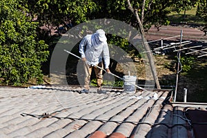 Worker adding undercoat foundation paint onto rooftop with roller at residential building in renovation photo