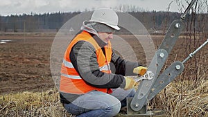 Worker with adjustable wrench near tensioner on field