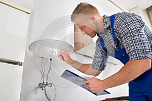 Worker Adjusting Temperature Of Water Heater