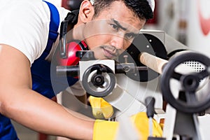 Worker adjusting turning machine in factory