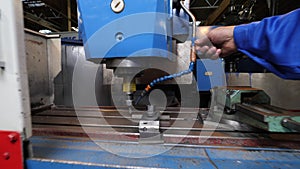 Worker adjusts cooling pipe on drilling machine tool in shop