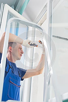 Worker adjusts the plastic window while standing on the stairs