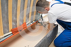 The worker adjusts the smoothness of the movement of the mechanism of the new sofa