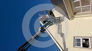 Worker on a aerial access platform, cherry picker, cleaning house