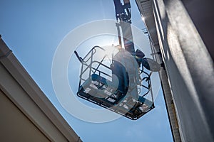 Worker on a aerial access platform, cherry picker, cleaning house
