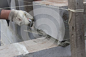 Worker aligns with a spatula, lay brick cinderblocks photo