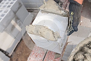 Worker aligns with a spatula, lay brick cinderblocks photo