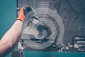 The worker aligns the wall with a tile adhesive applying it with a spatula