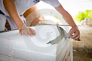 Worker applies the glue to thermal isolation material, styrofoam with spatula