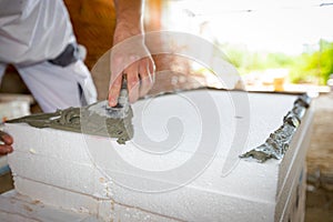 Worker applies the glue to thermal isolation material, styrofoam with spatula