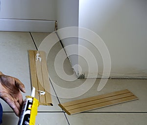 worker applies glue on wooden skirting board