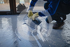 The worker applies gray epoxy resin to the new floor