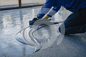 The worker applies gray epoxy resin to the new floor