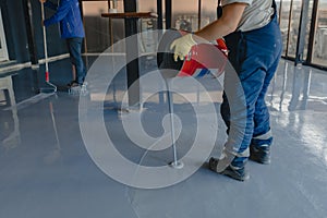 The worker applies gray epoxy resin to the new floor