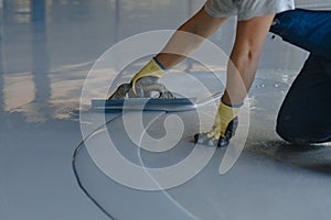 The worker applies gray epoxy resin to the new floor