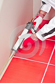 Worker applies silicone sealant on corner