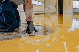 Worker apply coating floor with self-leveling epoxy resin in industrial deposit