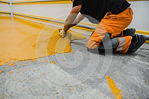 Worker applying epoxy and polyurethane flooring system