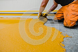 Worker applying epoxy and polyurethane flooring system photo