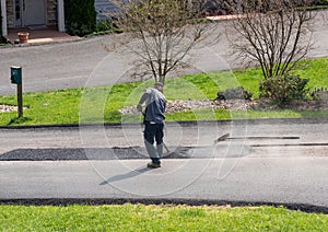 Worker applying extra blacktop to repair asphalt street