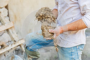 Worker applying mud plaster to a traditional stone house